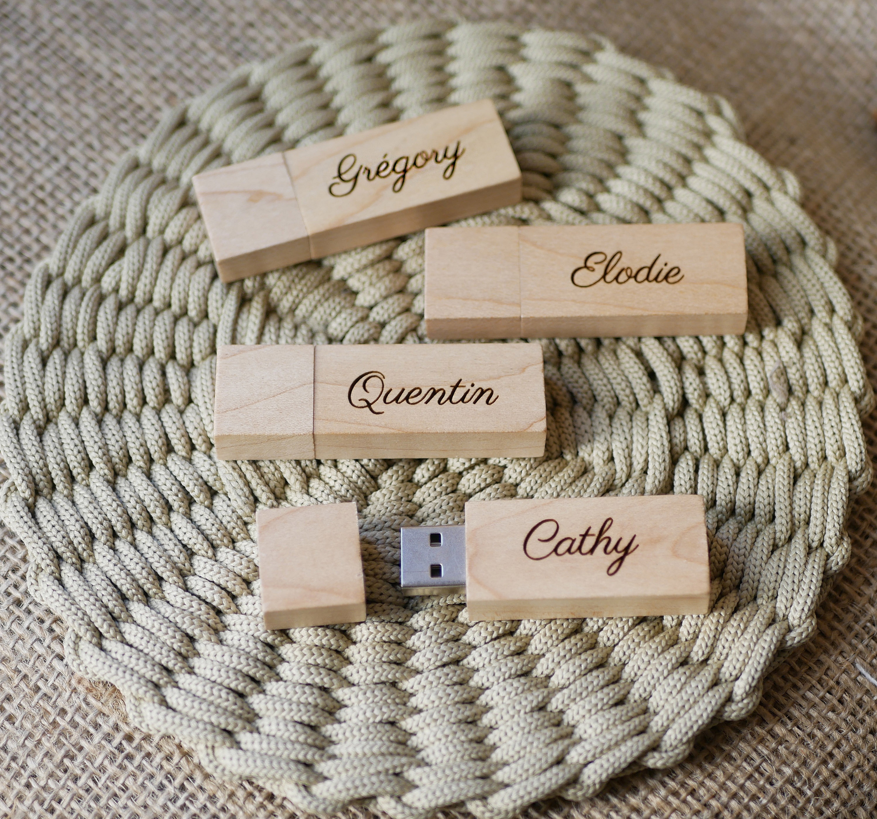 Clés USB en bois clair personnalisées avec prénoms gravés.