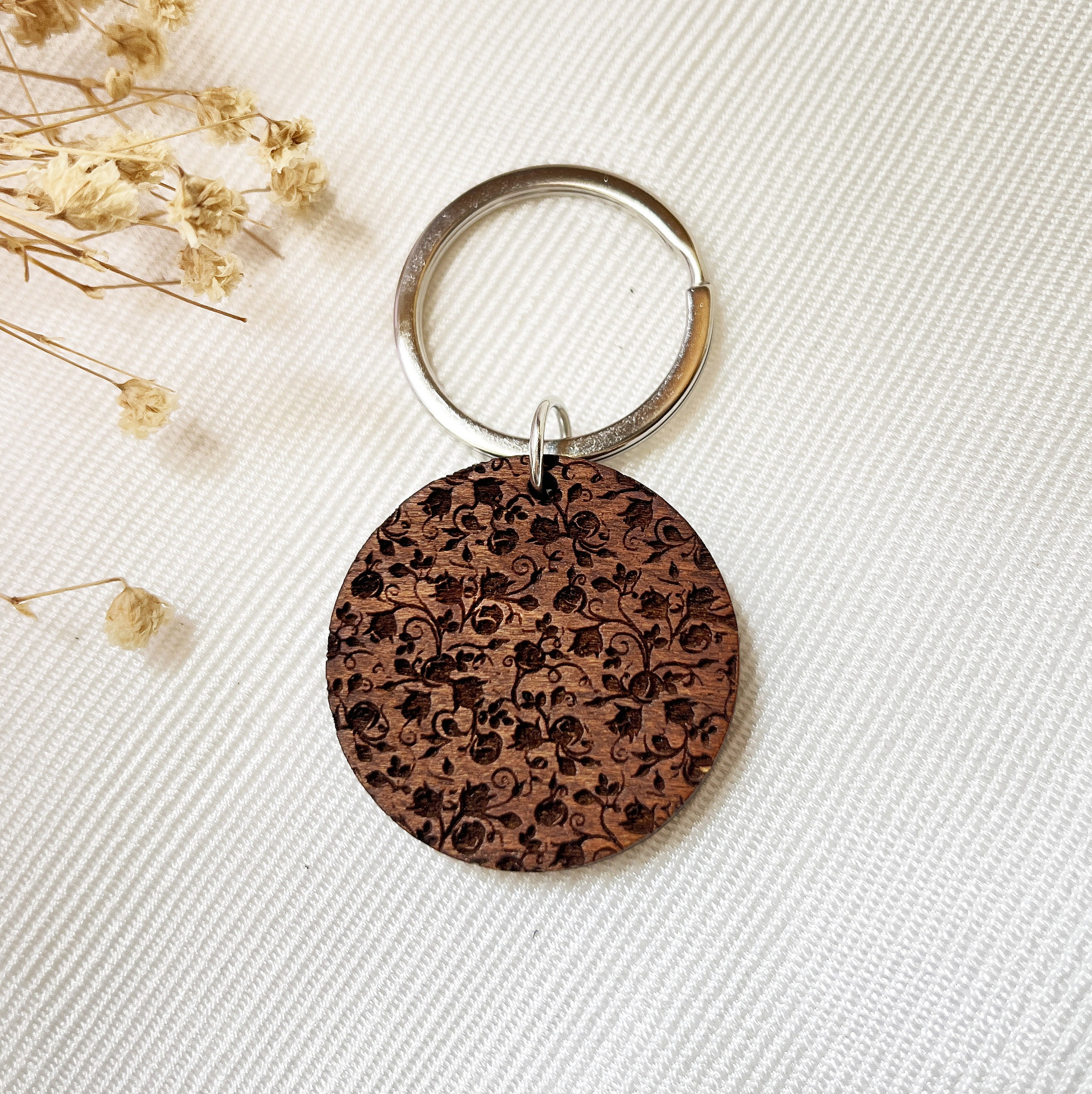 Porte-clé rond en bois gravé avec perle et breloque.